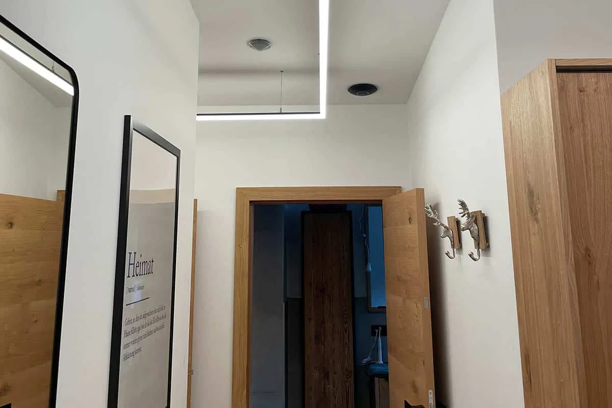 Heller Flur mit Holzdetails, Spiegel und moderner Deckenbeleuchtung. Einladende Atmosphäre.