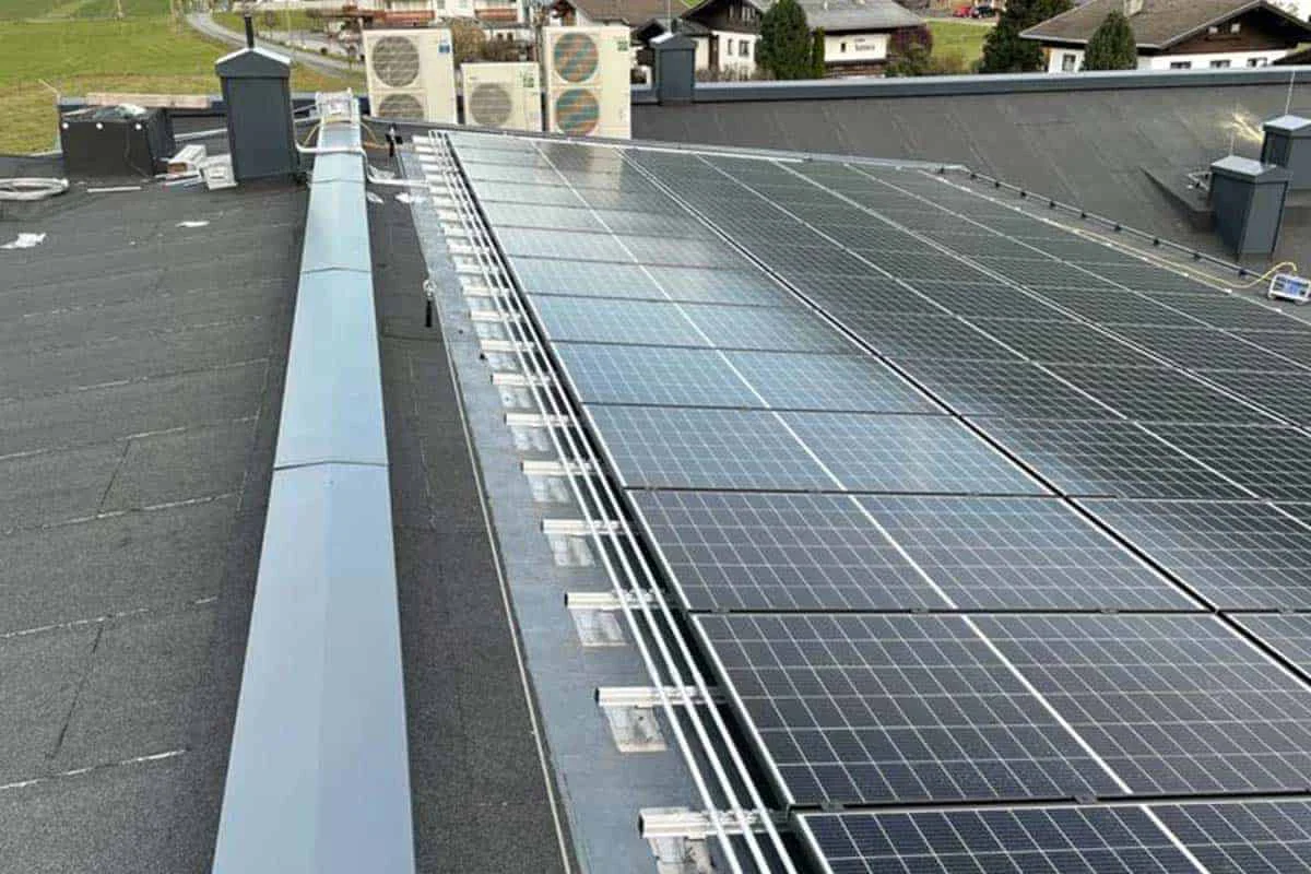 Photovoltaikanlage auf einem Dach mit mehreren Solarmodulen und angrenzenden Lüftungsgeräten.