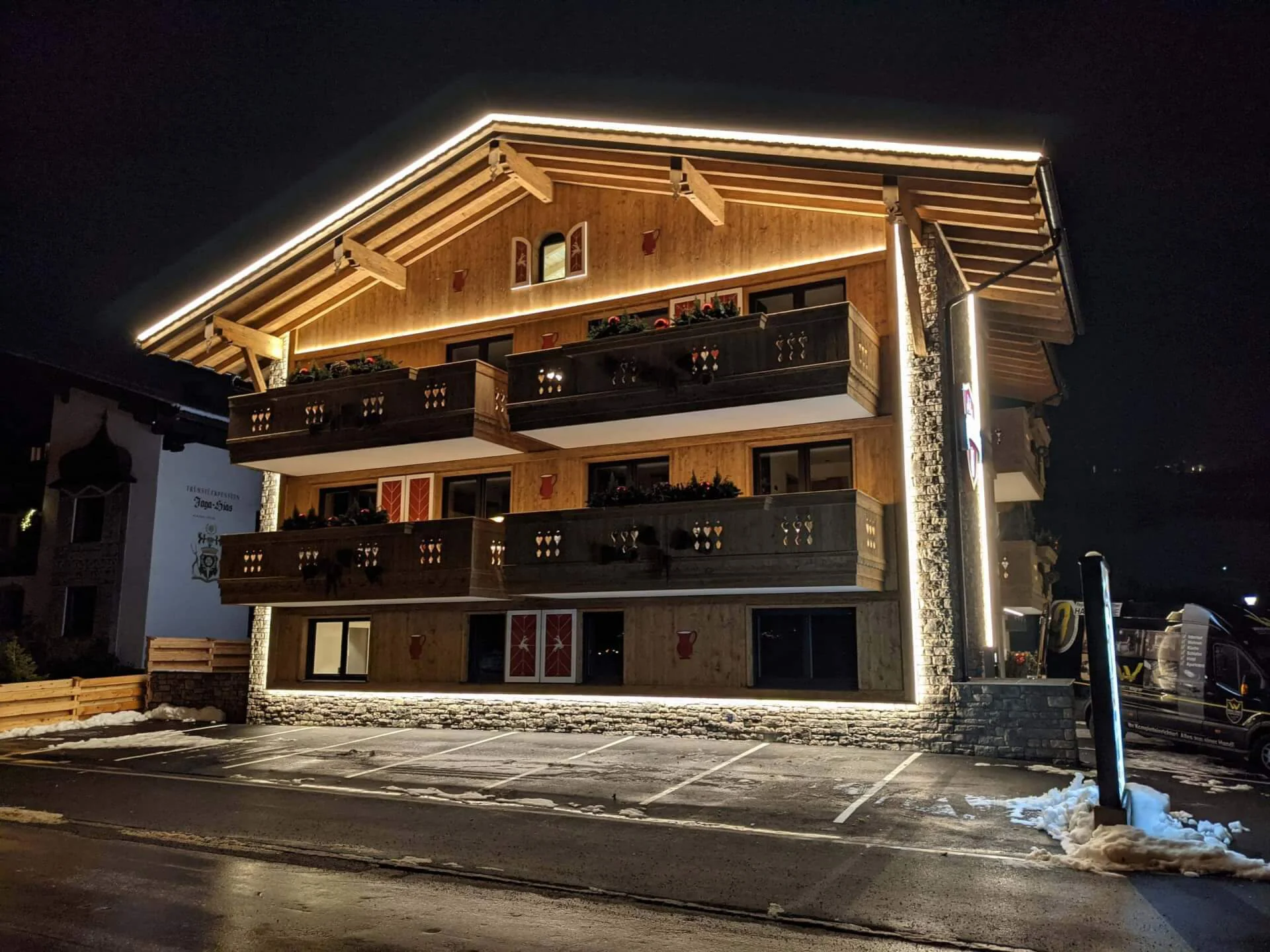 Alpenchalets mit stilvoller Beleuchtung und Holzfassade in nächtlicher Umgebung.